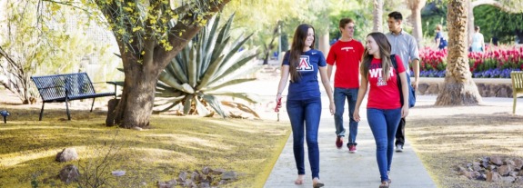 ae888 students walking on campus path near flowers and a shady tree